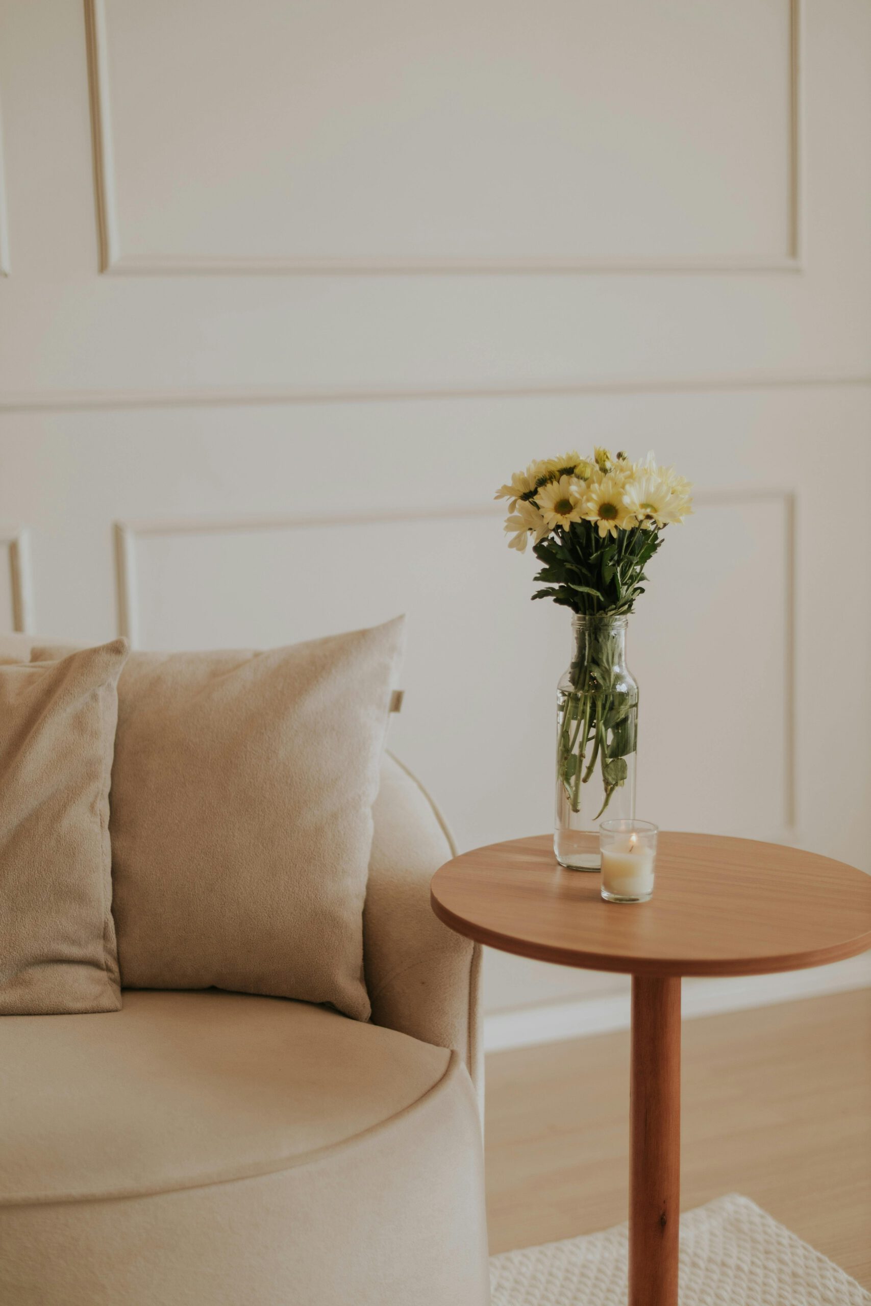 Serene minimalist living room interior featuring a cozy beige armchair and a vase of yellow flowers.