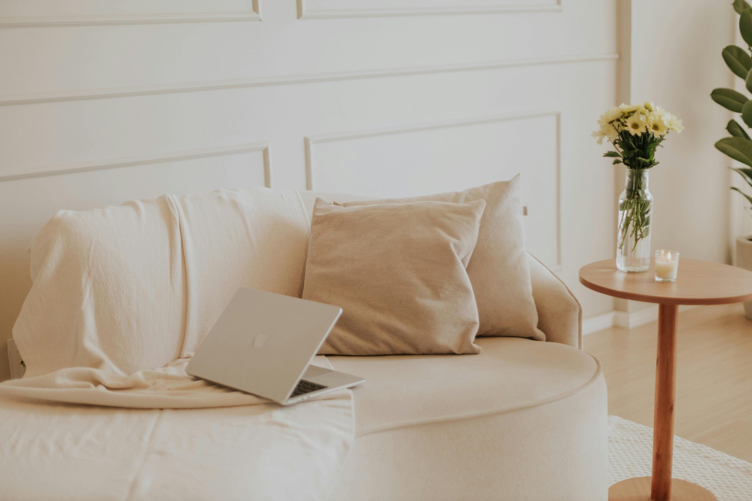 A serene minimalist living space with a laptop and flowers, perfect for remote work.